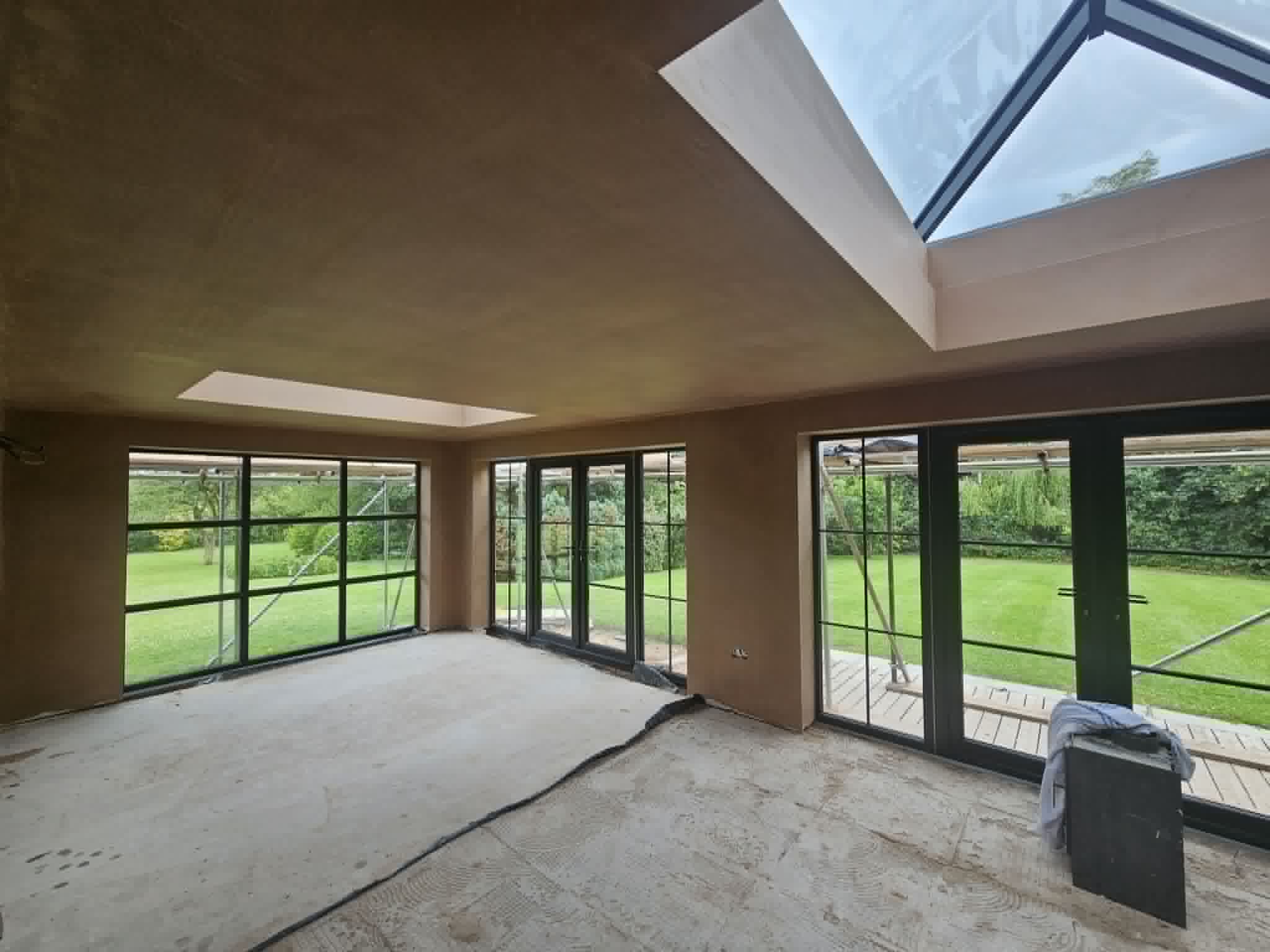 Newly plastered garden room with large black-framed windows